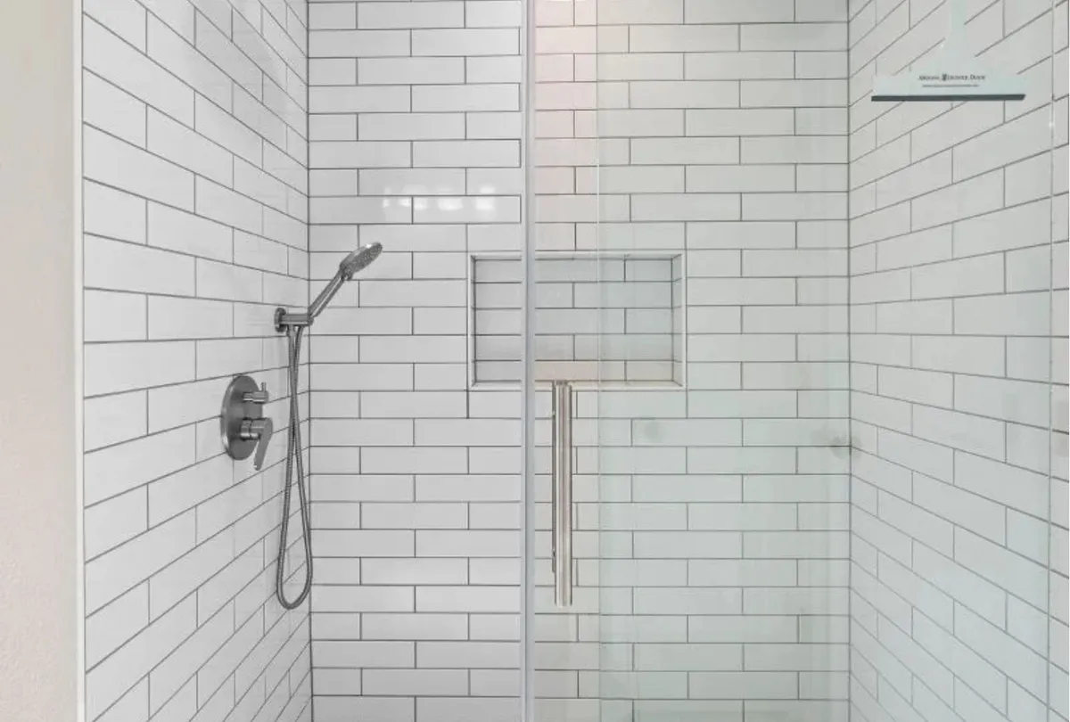 A modern shower with white subway tiles and a glass sliding door