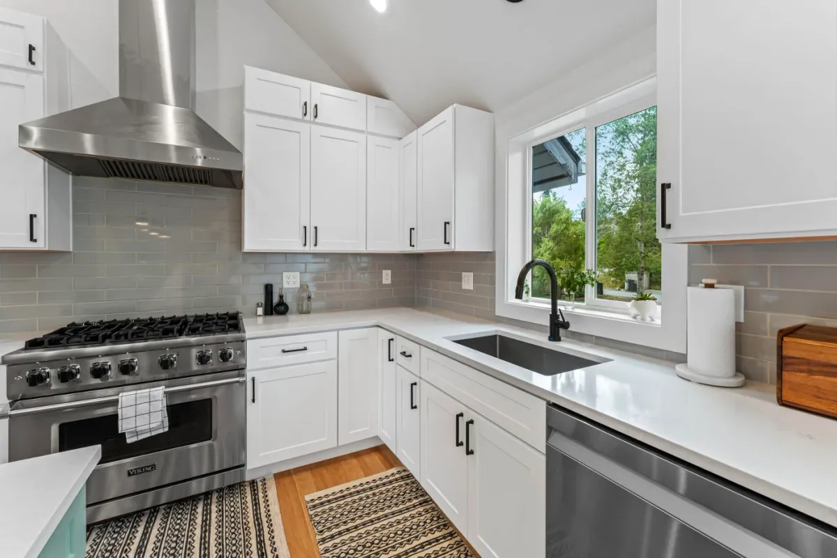 modern kitchen with white cabinets, a gray tiled backsplash, and a stainless steel range hood